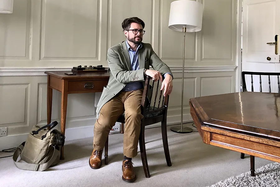 prof sits at wooden desk and looks into room