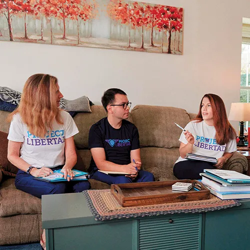 adults on sofa conversing with Project Libertad teeshirts