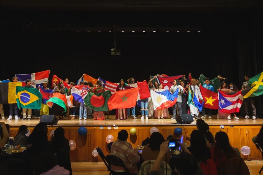international students on stage hold up all their different national flags