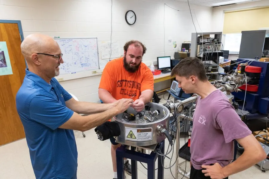 male prof and students in physics lab