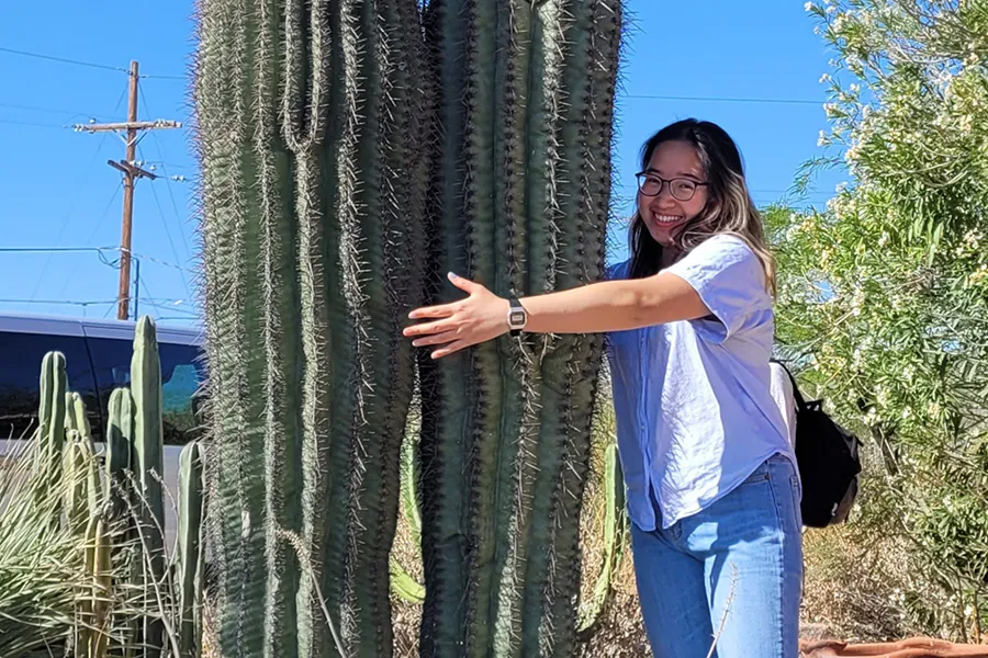 female student pretends to hug saguarro cactus