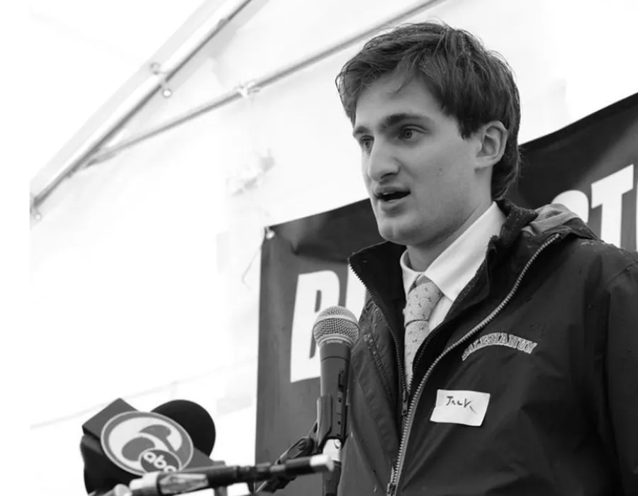 black and white photo of student in tie speaking at microphone
