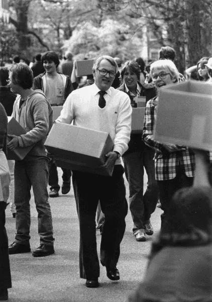 President Charles Glassick carring books to the library