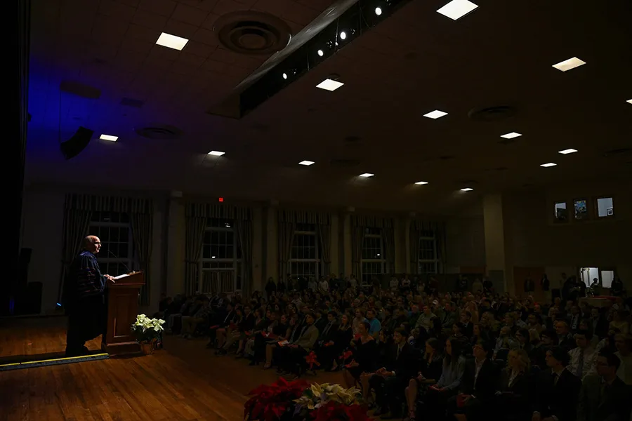president Iuliano speaks at podium in front of crowd in dimly lit ballroom