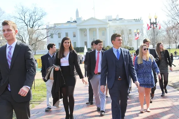 professionally dressed students walk  with White House in background