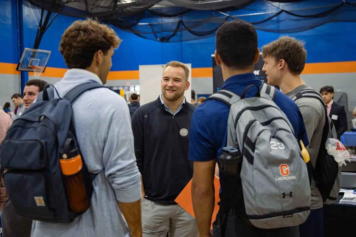 group of students talk with alum in gym converted to professional event