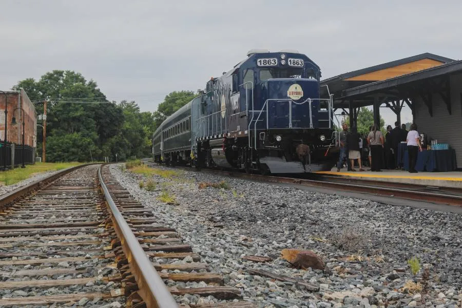 blue train engine pulls train on track