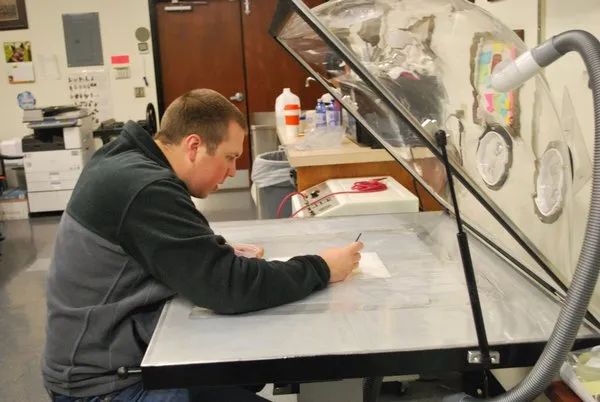 Tyler Black using the suction table to clean an 18th-century document