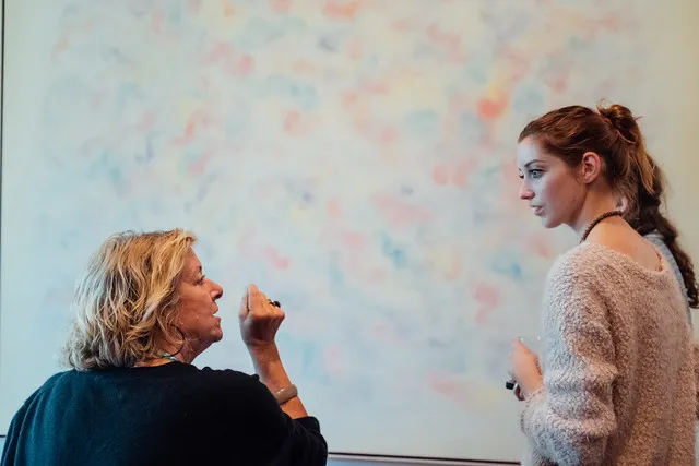 Two people discuss ideas beside a whiteboard.