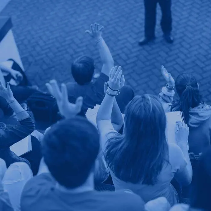A photo of a group of students raising their hands with a blue filter over it.