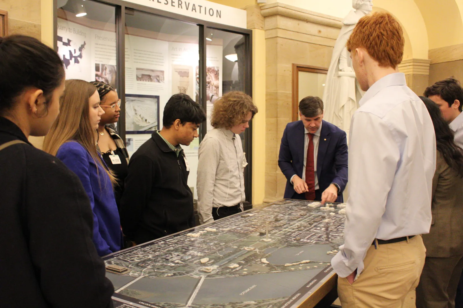 Students gathered around a tabletop model, examining its details.