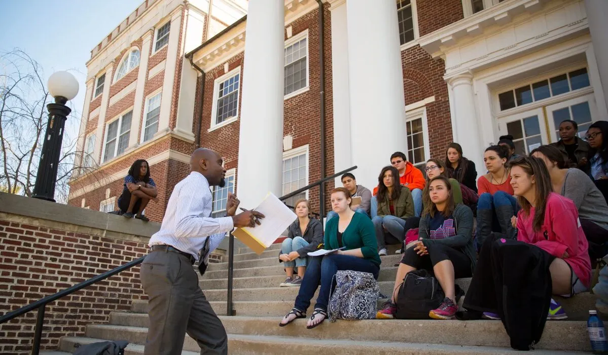 Prof lectures class outside building, on steps
