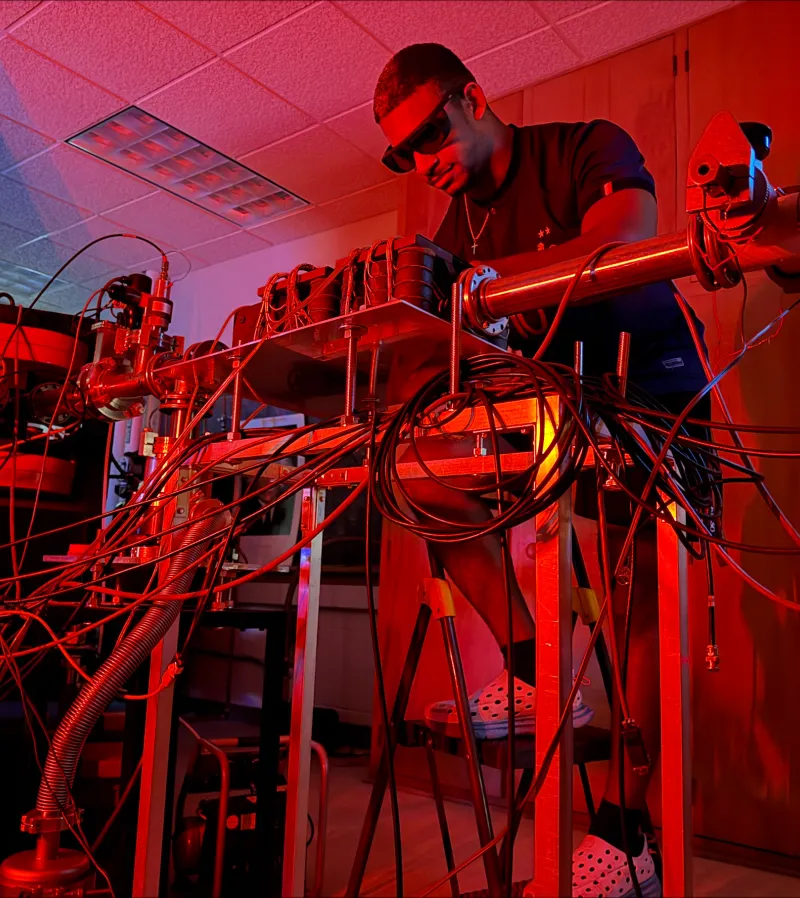 Christian Brutus stands behind electrical equipment in red light