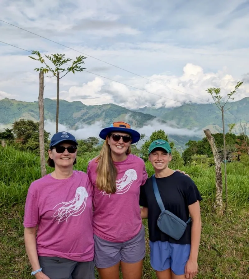 Katie LaPlaunt stands in front of mountains with faculty members