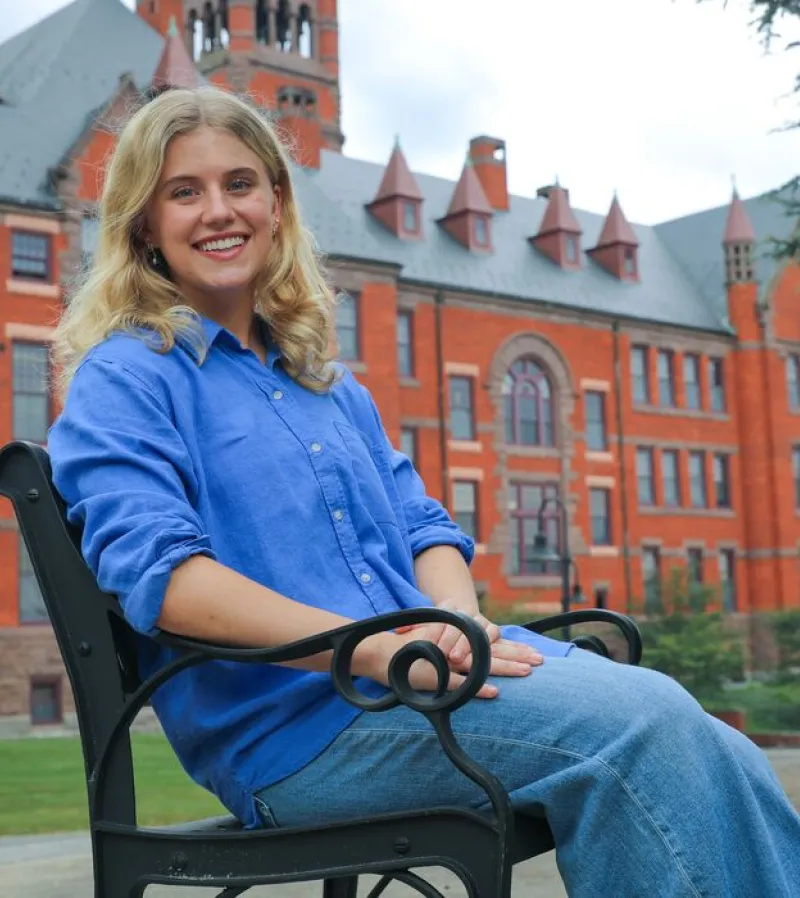 Paige McKim sits on bench in front of brick buildling