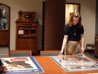 Two students examine posters in a library exhibit room.