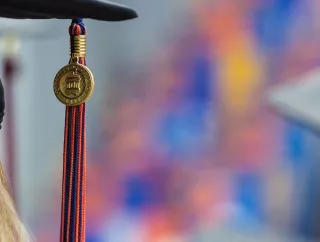 A close-up shows a graduate wearing a black mortarboard with a red-and-blue tassel