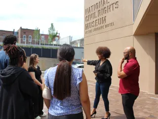 A group listens to a speaker outside the National Civil Rights Museum.