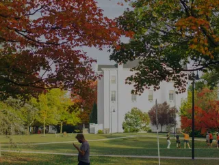 Autumn trees frame a campus walkway and building.