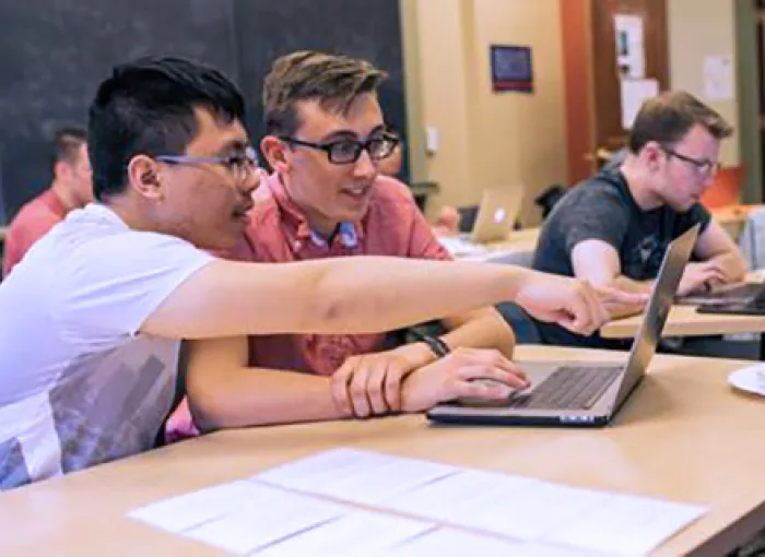 Two students looking at the laptop.