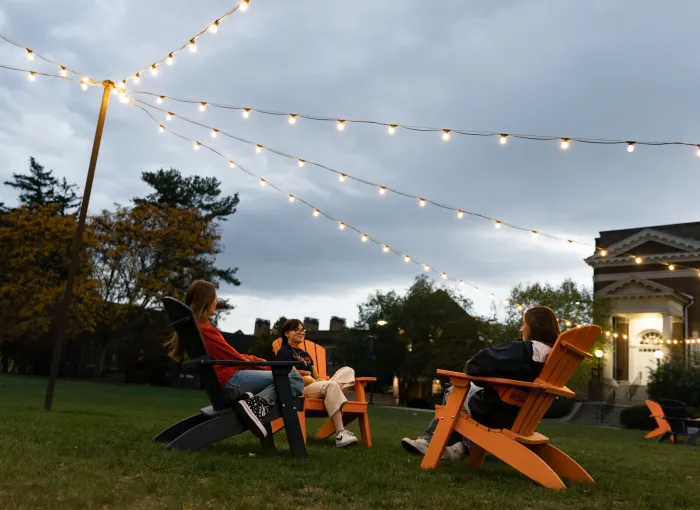students under lights in adirondack chairs