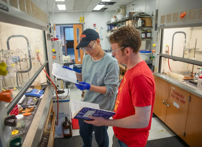 student and prof review chem notes in lab