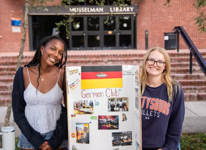 Two students stand at German activities table.
