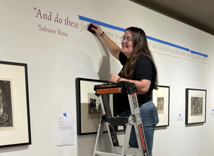 Student on ladder helps with gallery installation