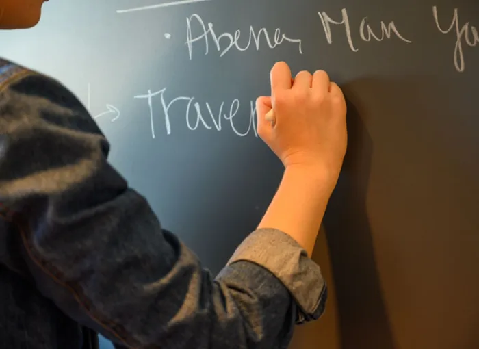 A student writes at a blackboard.