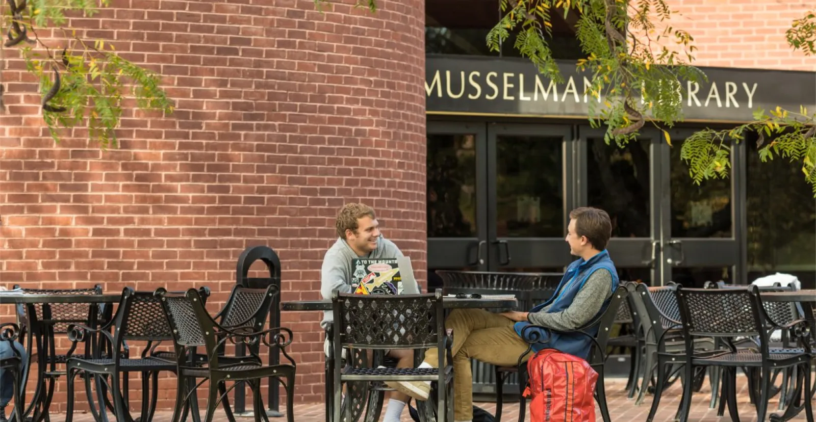 male students converse at outdoor table