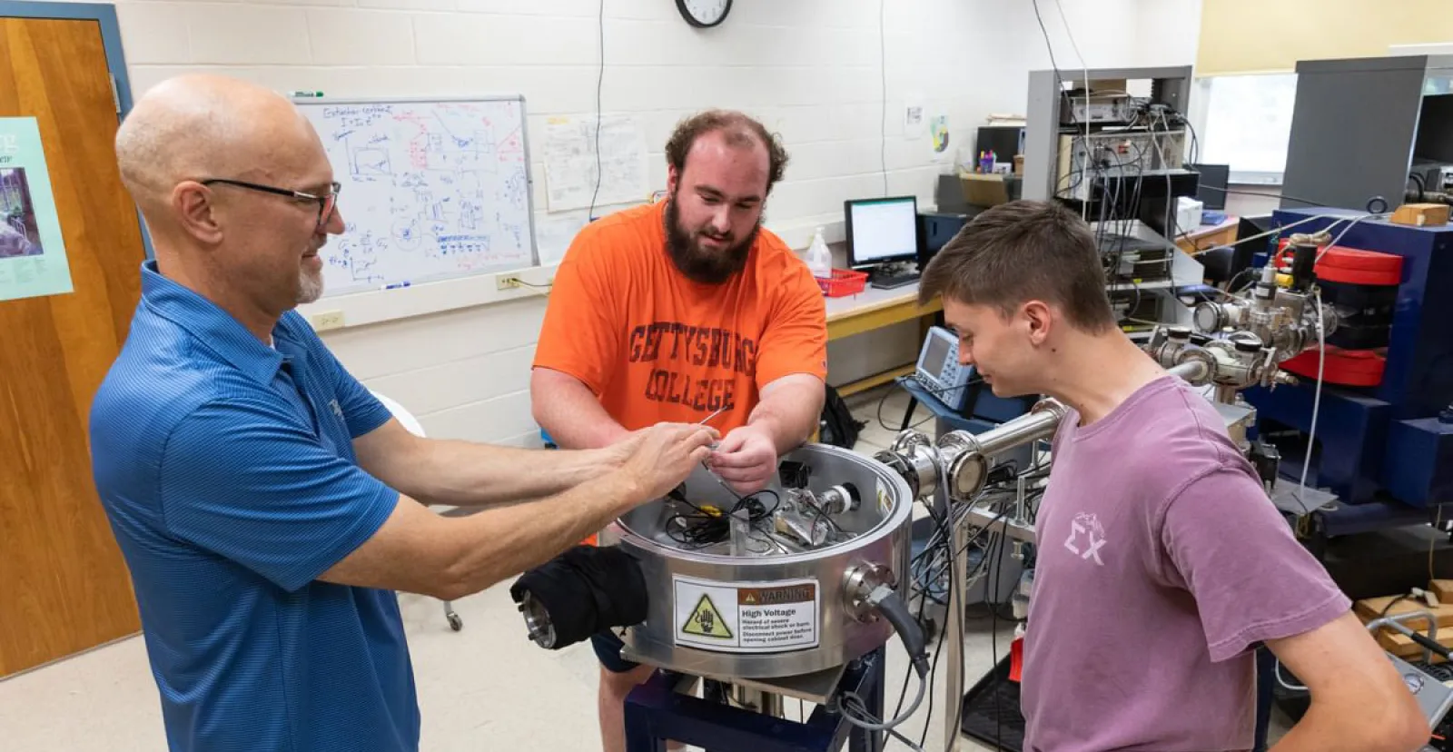 male prof and students in physics lab