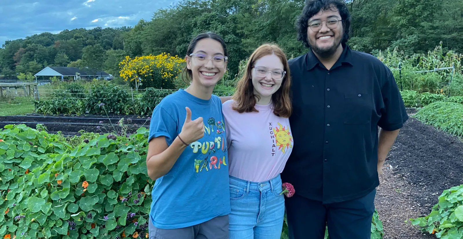 students pose together at Painted Turtle Farm in front of gardens