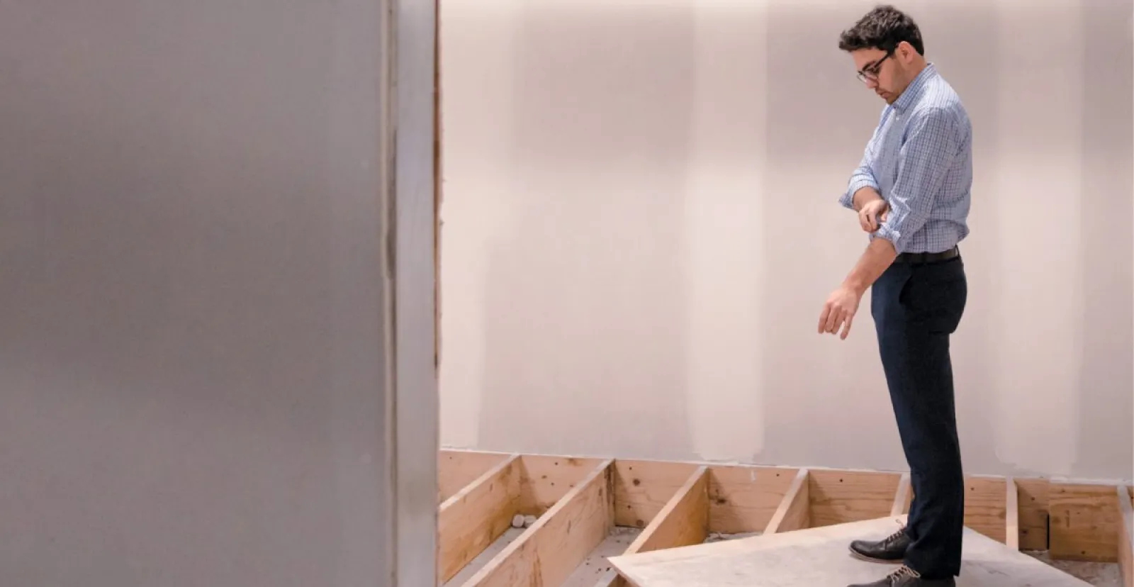 photo of Andrew Dalton standing on plywood looking down into open subfloor