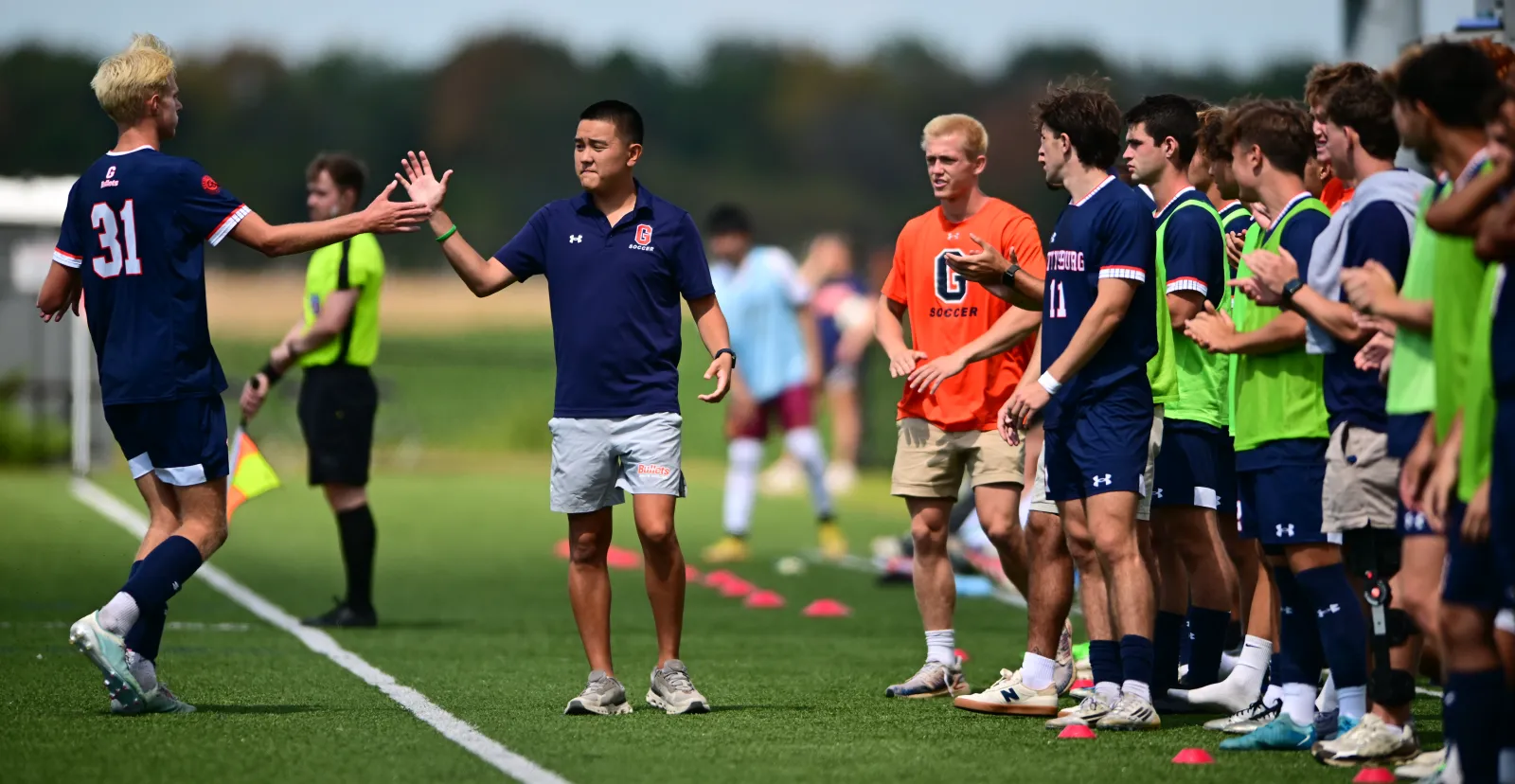 Men's soccer head coach Dan Malone gives a high-five to a player.