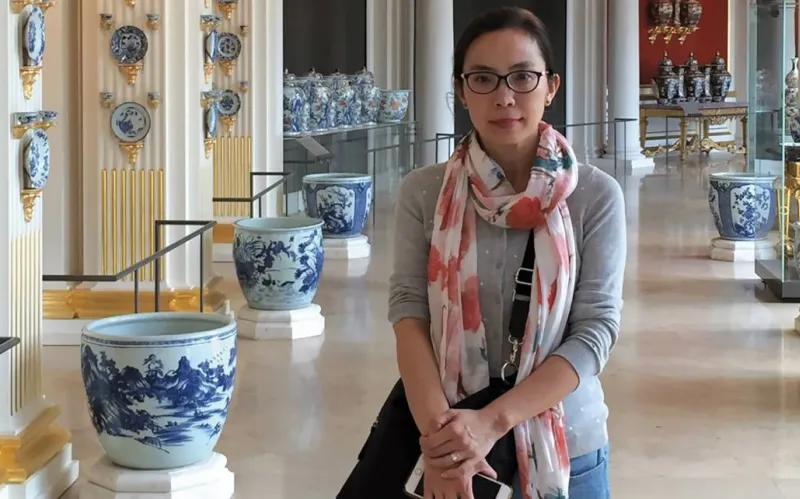 Yan Sun at a museum with asian pottery behind her in the background