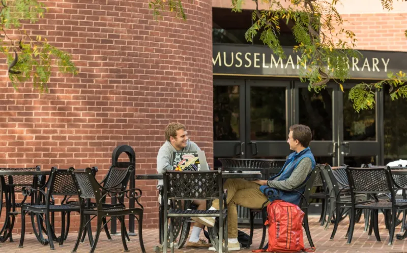 male students converse at outdoor table
