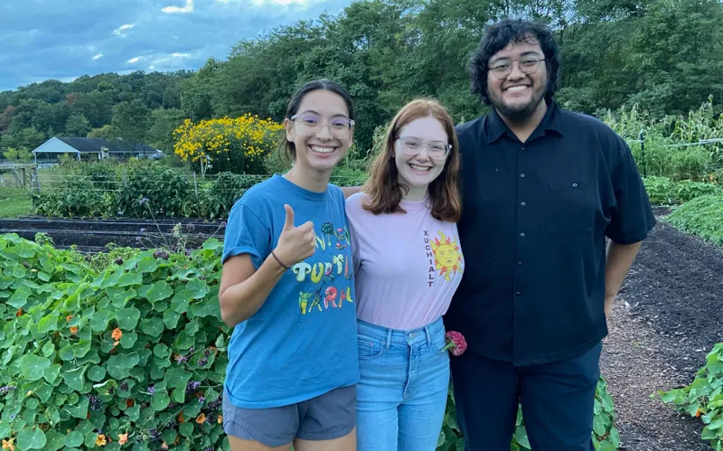 students pose together at Painted Turtle Farm in front of gardens