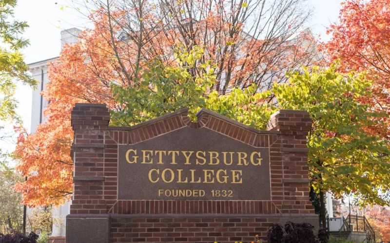 Gettysburg College sign on Washington Street with fall foliage in background