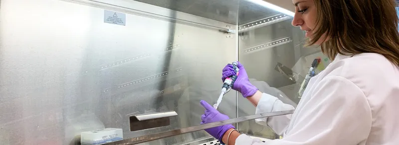 student pipettes under hood