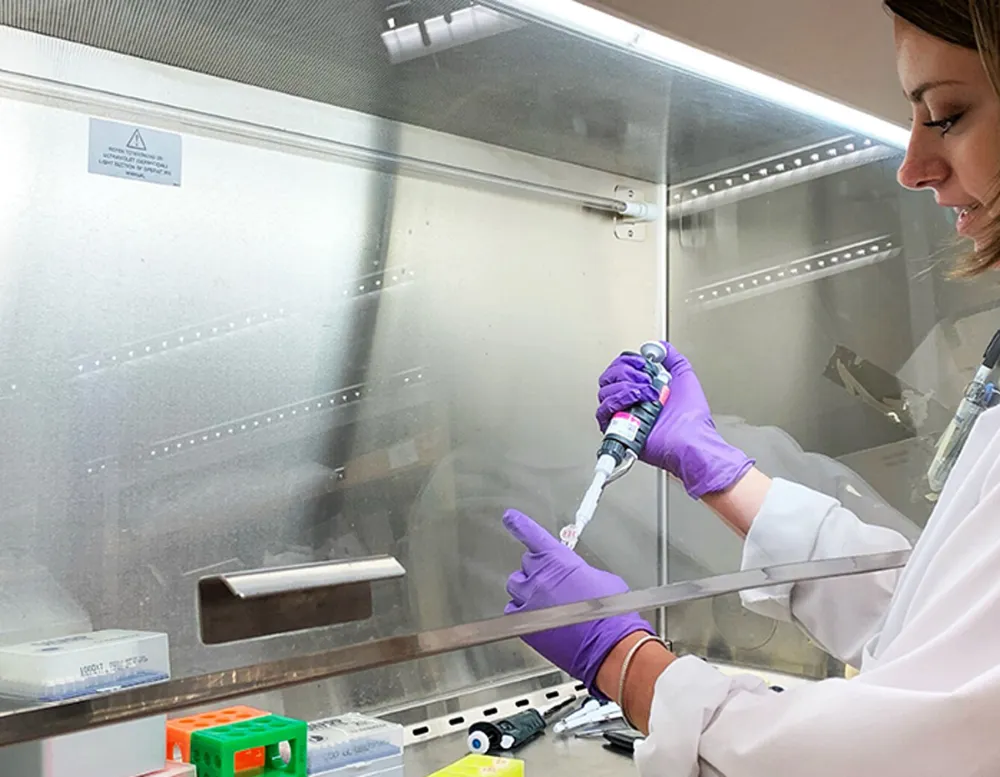 student pipettes under hood