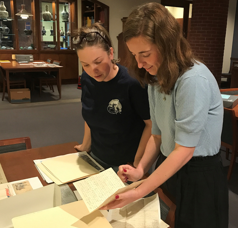 An alum and student examining Civil War Era letters at a research table in Special Collections